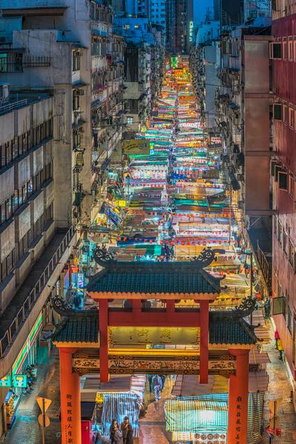 Aerial view of vibrant street market with colorful stalls and traditional gate