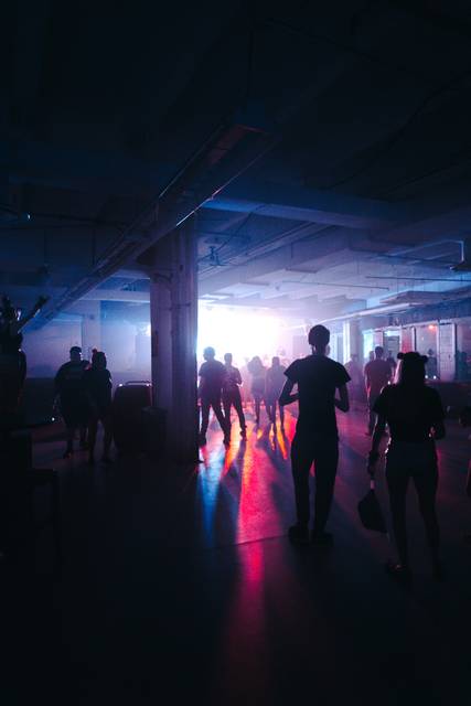 Silhouettes of people in atmospheric underground venue with colorful stage lighting