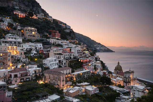 Positano Italy hillside village at sunset with colorful buildings overlooking the sea
