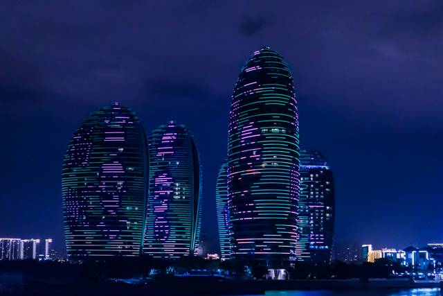 Futuristic illuminated towers with purple and green lights at dusk