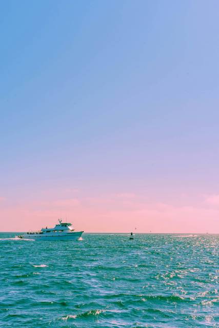 Luxury yacht on turquoise ocean at sunset with pink and blue sky
